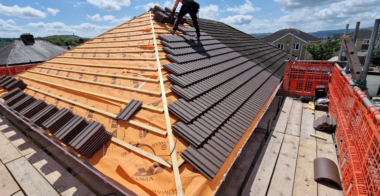 Roofer installing new concrete roof tiles over a breathable membrane during a re-roof