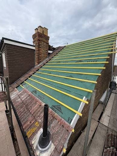 Breathable roofing membrane and battens fitted during a re-roof, with lead flashing dressed around the chimney base